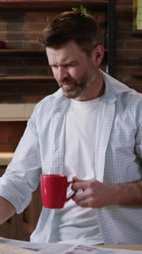 A Man Sitting Comfortably at Home Enjoying a Cup of Coffee While Reading His Newspaper