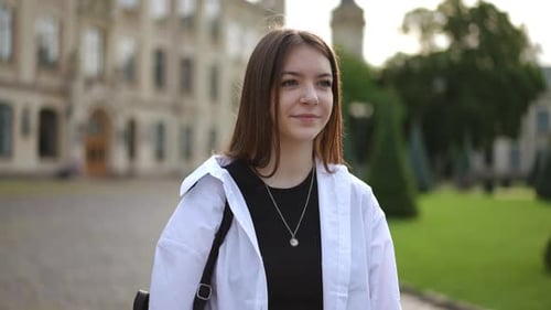 Slow Motion A Girl Walks Through the Institute Park Against the Backdrop of an Old Beautiful