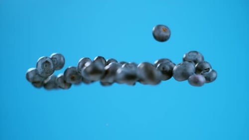 A group of blueberries launched in air with a single berry separated. High quality cinematic studio
