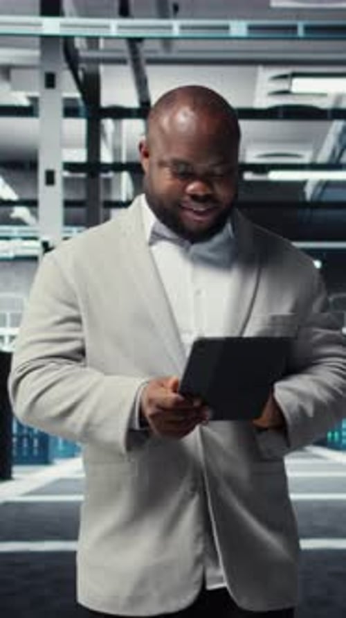 Vertical Video Happy Engineer Walking in Data Center Refining Algorithms on Tablet