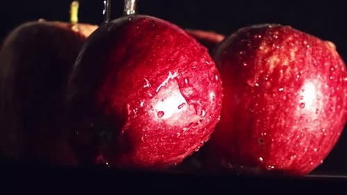 Nahaufnahme, Wassertröpfchen spritzen auf rote Äpfel. Studio mit schwarzem Hintergrund