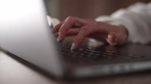Hands Typing on Laptop Keyboard in Office Setting
