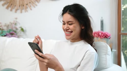 Smiling Woman Relaxing on Couch Using Smartphone
