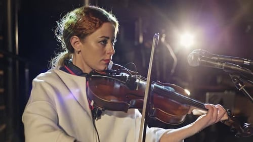 Woman Plays Violin Under Bright Stage Lights