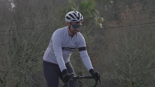 Mann radelt tagsüber mit Helm und Sonnenbrille auf einer Landstraße