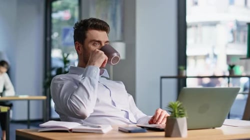 Man Drinking Coffee at Desk in Office