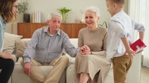 Happy Family Grandchildren Gives Gift Box Spring Tulip Flowers to Grandparents Smiling Kids Children