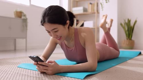 Woman Using Smartphone on Yoga Mat at Home