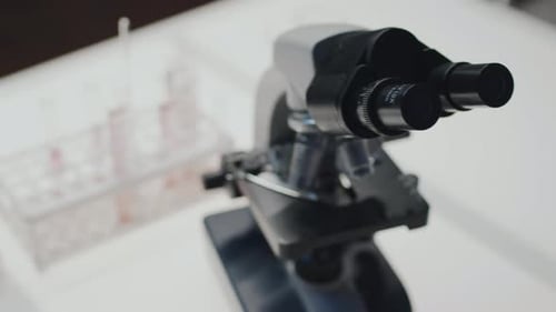 Microscope in Scientific Laboratory with Testing Vials