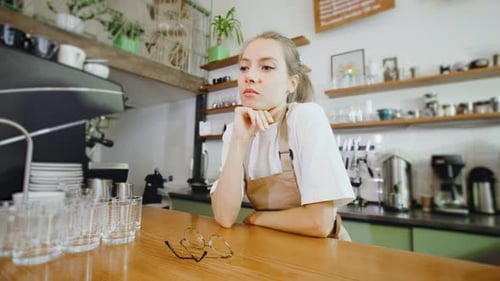 In a Cozy and Friendly Cafe a Tired Barista Girl is Leaning Against the Counter Taking a Brief
