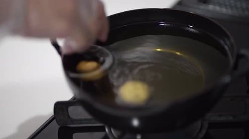 Dough Frying in Oil in a Black Pot