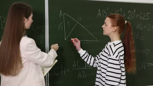 Student Solving Math Problem With Teacher in Classroom