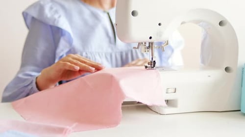Woman clothing designer sews fabrics on a sewing machine.