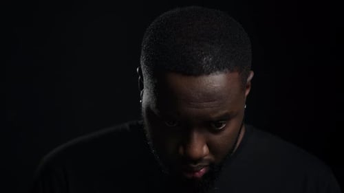 Closeup Focused Man Raising Head on Black Background. Portrait of African American