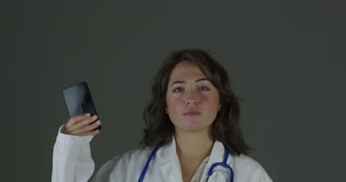 Young Woman Doctor Holds Up Smartphone