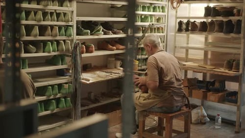 Senior Cobbler Working with Assistant in Shoemaking Workshop