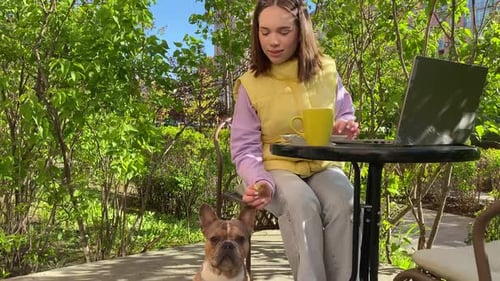 Charming Woman Shares Food with Dog While Working at Cafe Outdoors