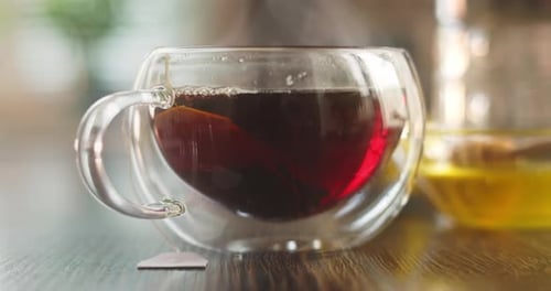 Dampfende heiße Teetasse Heißer Tee in einer Glastasse mit Rauch auf einem Holztisch in der Küche