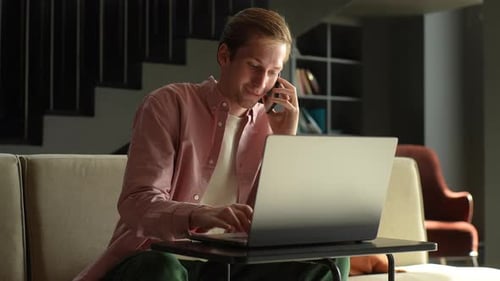 Young Man Using Laptop and Smartphone on Couch
