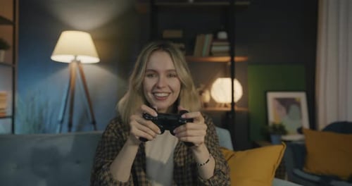 Porträt eines fröhlichen Mädchens, das ein Videospiel spielt und in die Kamera schaut und Spaß in der Wohnung hat