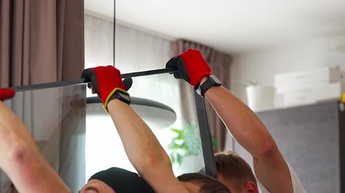 Workers Lifting Large Glass Panel From Horizontal to Vertical Position Before Window Installation