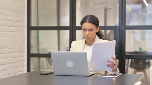 Woman Analyzes Paperwork at Desk in Office