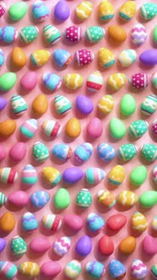 Looping video of colorful painted easter eggs on a wooden pink table animated in stop motion style