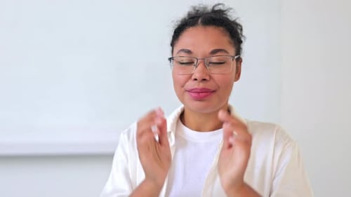 Smiling woman puts on glasses, looks at camera
