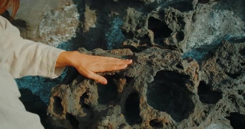 Woman touching porous volcanic rock surface during contemporary dance performance
