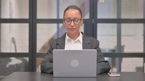 Professional Woman Smiling in Office with Laptop