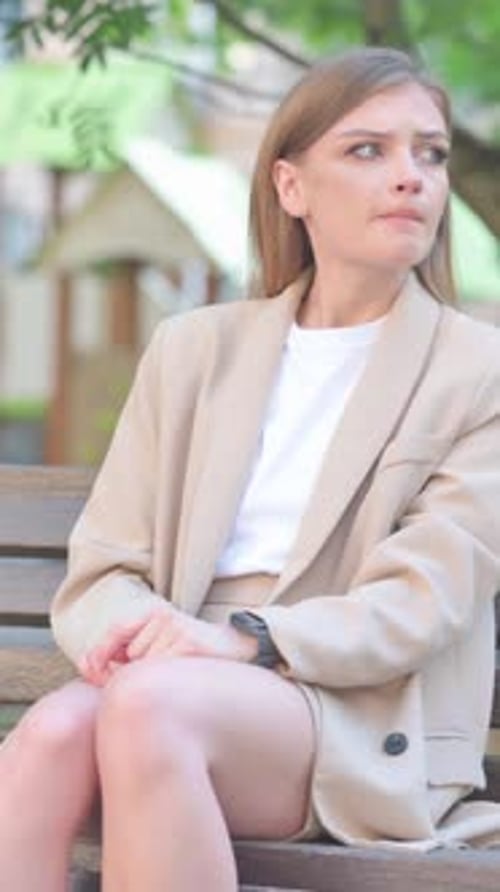 Woman Sits on Bench Checking Smart Watch Outdoors