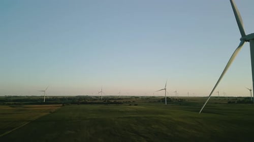 Aerial Wide Drone View of a Wind Farm Park with Wind Turbines Standing in a Wheat Field at Sunset