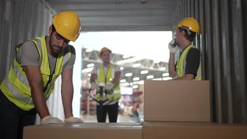 Blue collar workers are working at warehouse.