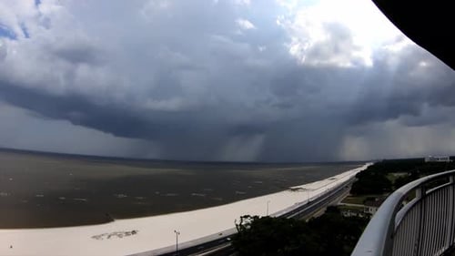 tempête de pluie accélérée alors que d'énormes nuages passent et que de fortes pluies tombent sur l'océan ; vue de la balustrade du 14e