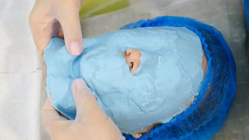 Professional Cosmetologist Peeling Off Facial Alginate Mask From Female Face in Beauty Spa Salon