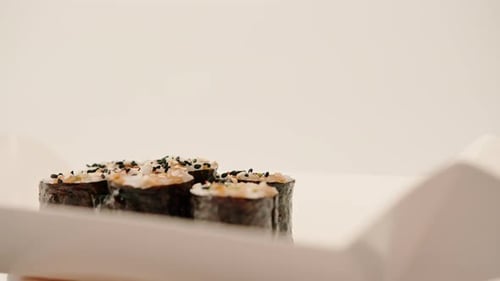 Close-up of maki roll with avocado with soy sauce in sushi delivery box on white background