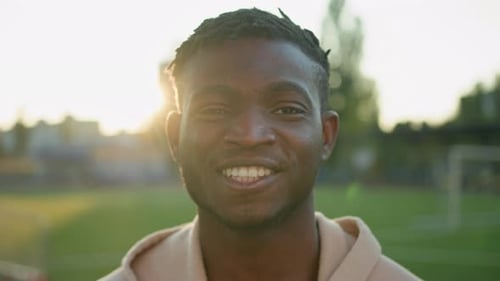 Young Man Smiling in Sunlight on Outdoor Field
