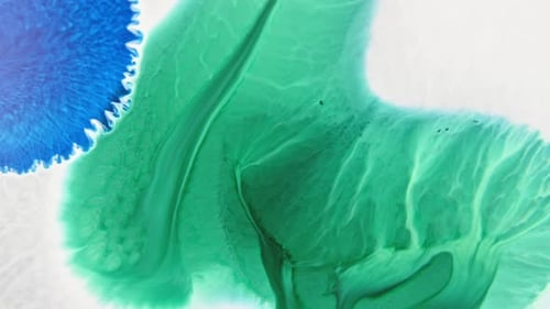 Close-up of vibrant blue and green ink patterns merging in water, creating an abstract art effect