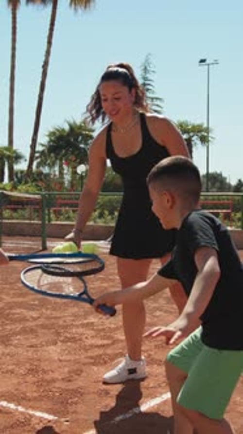 Woman Instructor And Children Pass The Ball With Tennis Rackets