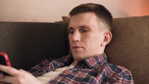 Man Relaxing on Couch with Smartphone Close-Up