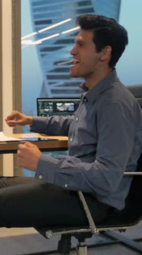 Young Man Celebrating Success at Office Desk