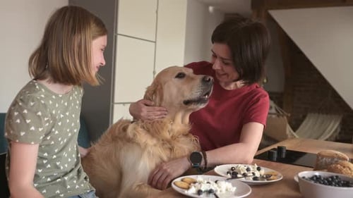 Woman and Girl Petting Dog at Kitchen Table