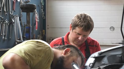 Profile of Two Mechanics Works with Car at Garage Portraits of Repairmans Fixing Vehicle at Workshop