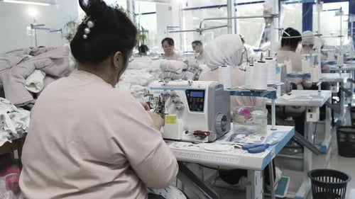Textilarbeiter nähen in der Fabrik an Industriemaschinen und konzentrieren sich auf die Herstellung von Kleidungsstücken