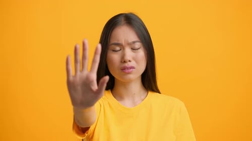 Woman Makes a Stop Gesture Against a Bright Yellow Urban Backdrop