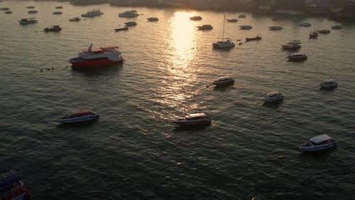 El resplandor dorado del atardecer se refleja sobre un concurrido puerto con barcos