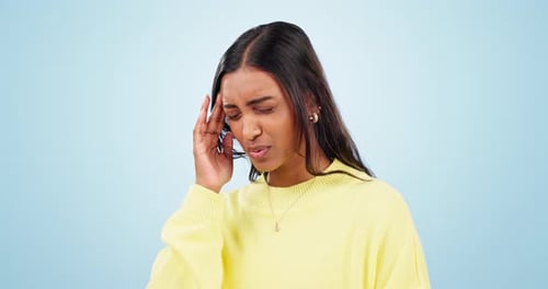 Stress, headache and woman with anxiety in studio worry, fear or burnout on blue background