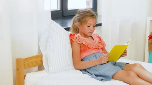 People, Childhood and Leisure Concept - Happy Little Girl Reading Book At