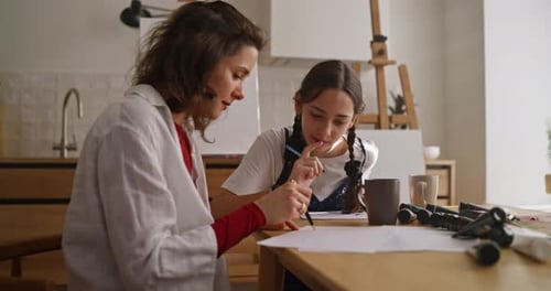 Woman and Girl Drawing Together at Table Indoors