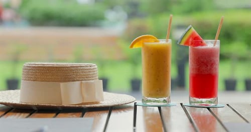 Straw Hat on Wooden Table Next to Refreshing Orange and Watermelon